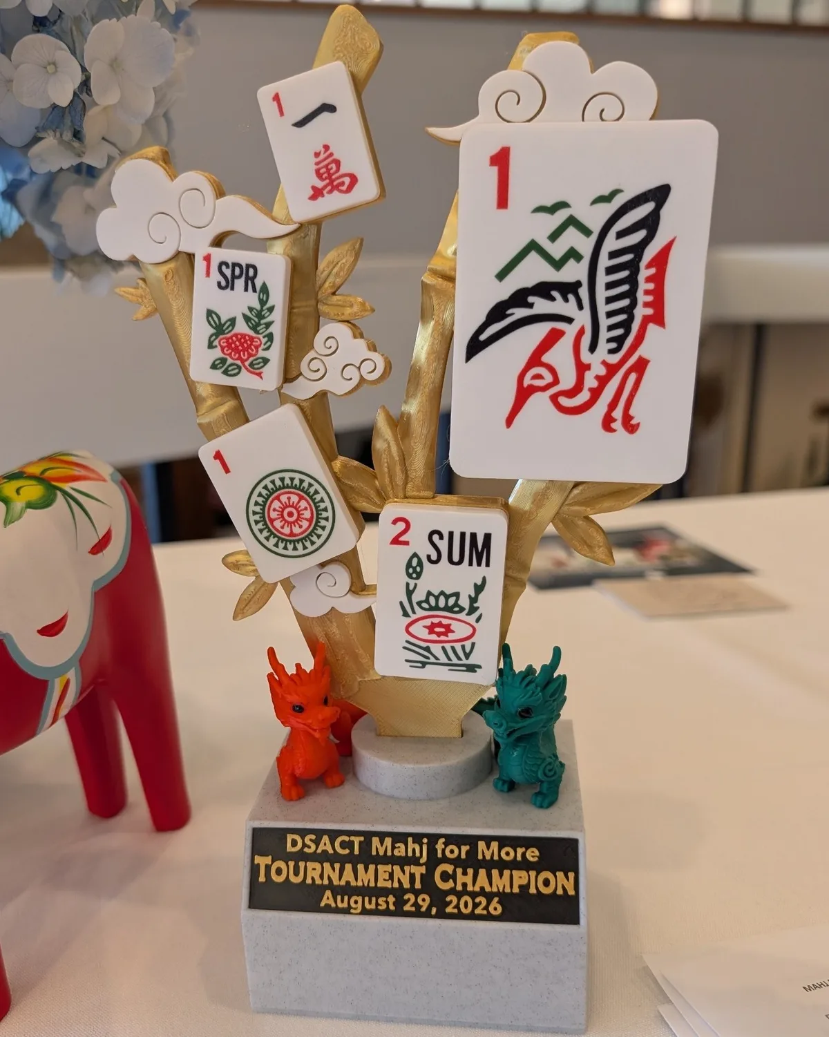 The Mahj for More champion trophy — mahjong tiles on gold bamboo with a pair of dragons at the base
